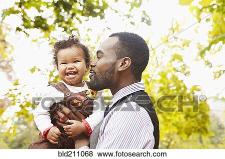 Stock Photo - Father holding toddler daughter in park. Fotosearch