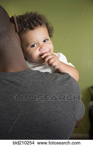 Picture - Father holding toddler son in bedroom. Fotosearch