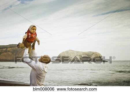 Father lifting baby son overhead at beach View Large Photo Image Stock Photograph - Father lifting baby son overhead at beach. Fotosearch