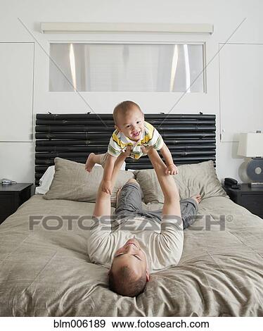 Father lifting son on bed in bedroom View Large Photo Image Stock Photo - Father lifting son on bed in bedroom. Fotosearch