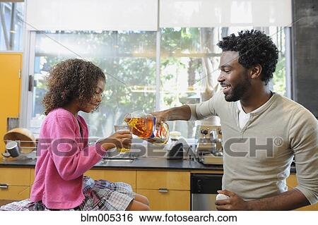 Father pouring juice for daughter View Large Photo Image Stock Photograph - Father pouring juice for daughter. Fotosearch