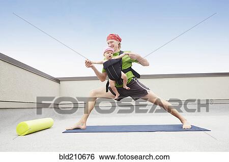 Stock Photograph - Father practicing yoga and holding baby. Fotosearch