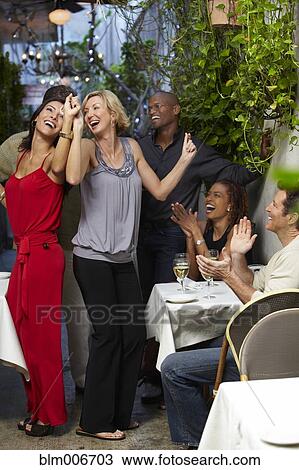 Stock Image - Friends dancing on restaurant patio. Fotosearch