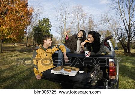 Friends eating pizza in back of truck View Large Photo Image Stock Photography - Friends eating pizza in back of truck. Fotosearch