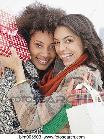 Friends hugging and holding Christmas gifts View Large Photo Image Stock Image - Friends hugging and holding Christmas gifts. Fotosearch
