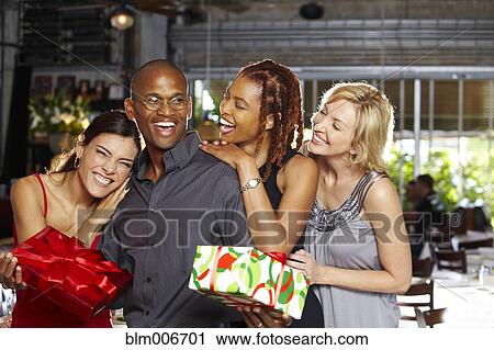 Stock Image - Friends laughing and holding birthday gifts. Fotosearch