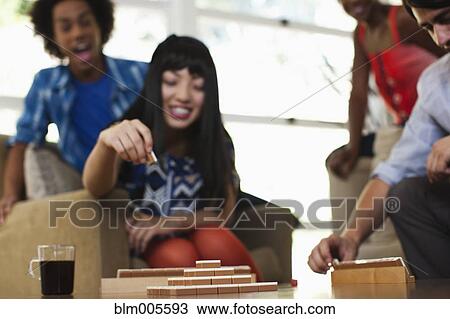 Stock Image - Friends playing mahjong at party. Fotosearch