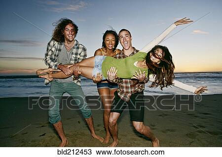 Stock Image - Friends posing together on beach. Fotosearch