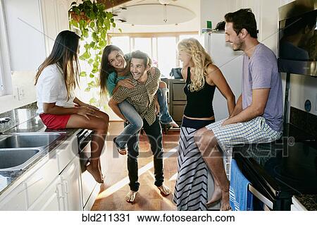 Stock Image - Friends relaxing together in kitchen. Fotosearch