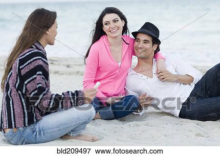 Stock Photo - Friends relaxing together on beach. Fotosearch