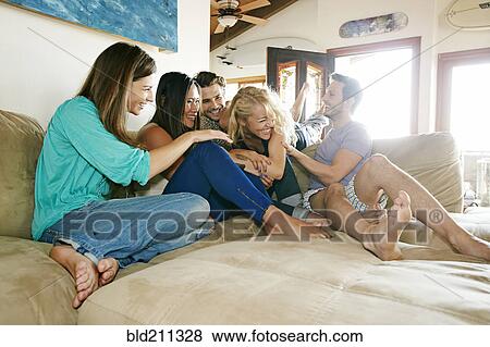 Friends relaxing together on sofa View Large Photo Image Stock Photo - Friends relaxing together on sofa. Fotosearch