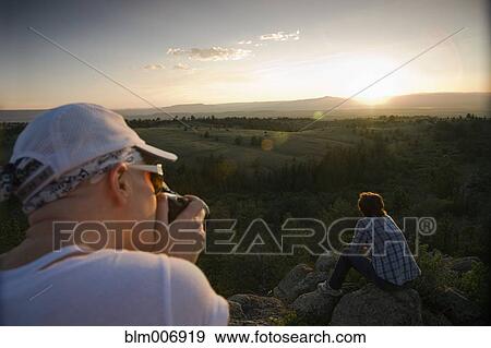 Stock Photo - Friends resting on rocks in remote area. Fotosearch