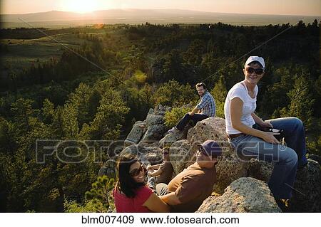 Friends resting on rocks in remote area View Large Photo Image Stock Photo - Friends resting on rocks in remote area. Fotosearch
