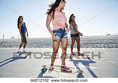 Stock Image - Friends riding longboards on beach. Fotosearch