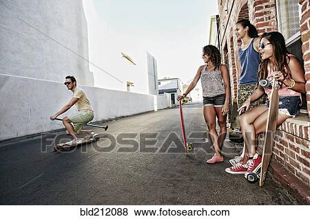 Stock Photo - Friends riding longboards on city street. Fotosearch