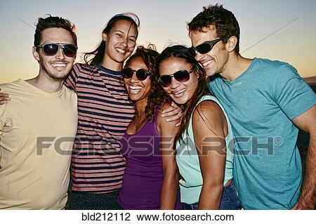 Stock Image - Friends smiling together on beach. Fotosearch