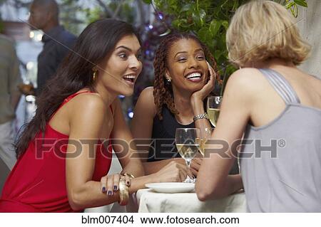 Picture - Friends talking over dinner in restaurant. Fotosearch