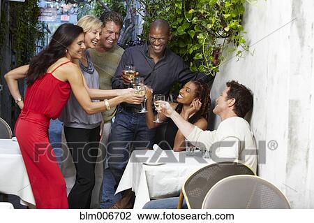 Stock Image - Friends toasting on restaurant patio. Fotosearch