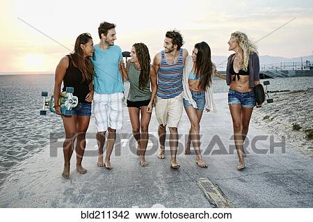 Stock Image - Friends walking together on beach. Fotosearch