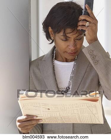 Stock Image - Frustrated African businesswoman reading newspaper. Fotosearch