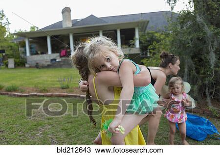 Stock Image - Girl carrying sister outdoors. Fotosearch