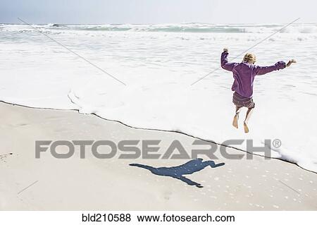 Girl playing in waves on sunny beach View Large Photo Image Stock Photo - Girl playing in waves on sunny beach. Fotosearch
