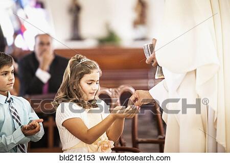 Stock Image - Girl taking her first communion at church. Fotosearch