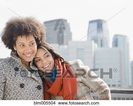 Picture - Girlfriends hugging in city. Fotosearch