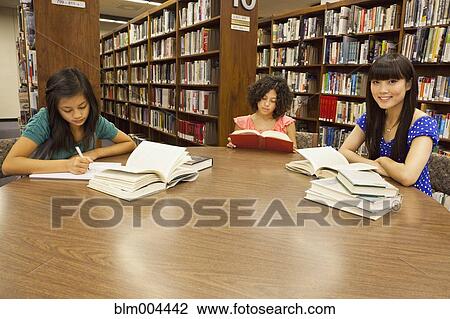 Stock Image - Girls doing homework in library. Fotosearch