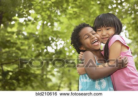 Stock Photograph - Girls hugging outdoors. Fotosearch
