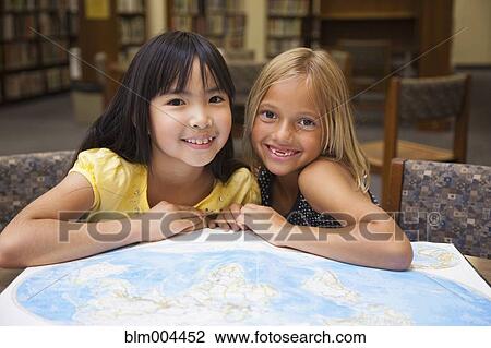Girls looking at atlas in library View Large Photo Image Stock Image - Girls looking at atlas in library. Fotosearch