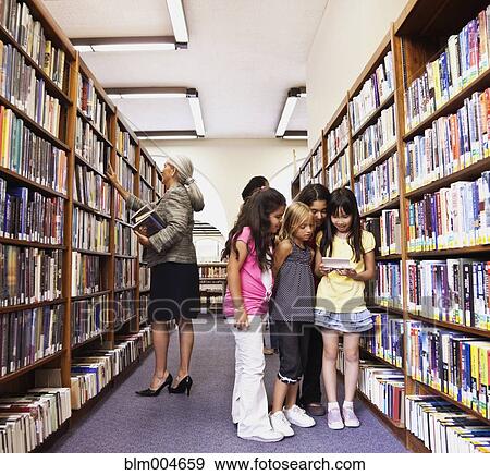 Stock Photo - Girls looking at video game in library. Fotosearch