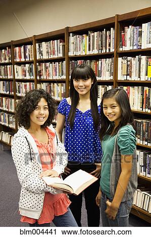 Stock Image - Girls standing in library. Fotosearch
