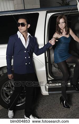 Stock Image - Glamorous couple getting out of car. Fotosearch