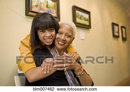 Stock Image - Grandmother and granddaughter hugging in gallery. Fotosearch