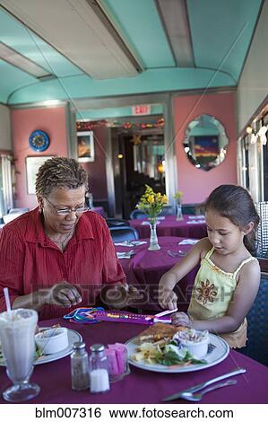 Stock Photograph - Grandmother and granddaughter playing with toy in restaurant. Fotosearch