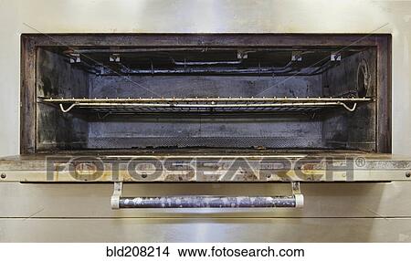 Picture - Greasy electric stove oven door open in aging commercial kitchen. Fotosearch