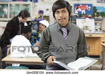 High school student holding text book in classroom View Large Photo Image Picture - High school student holding text book in classroom. Fotosearch