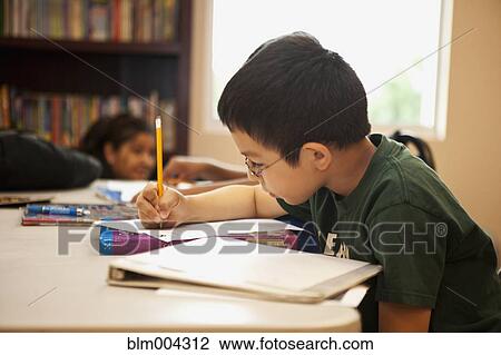 Stock Image - Hispanic boy doing homework in library. Fotosearch