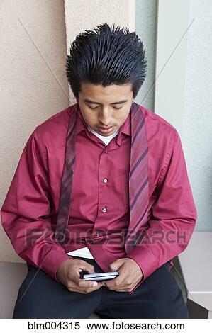 Stock Photography - Hispanic boy text messaging with cell phone. Fotosearch