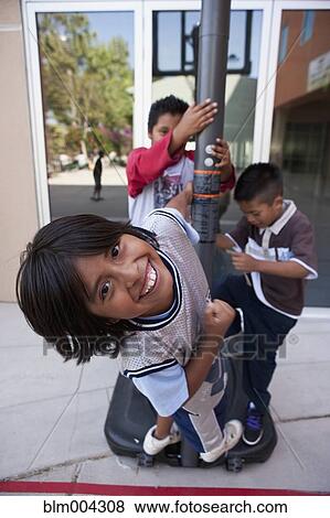 Stock Photo - Hispanic boys hanging on basketball post. Fotosearch