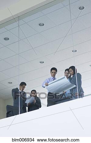 Picture - Hispanic business people looking at blueprint. Fotosearch