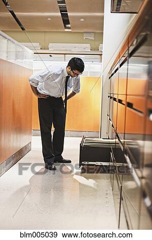 Stock Photo - Hispanic businessman looking in filing cabinets. Fotosearch