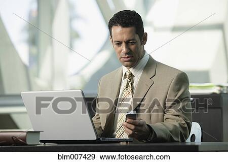 Hispanic businessman text messaging on cell phone View Large Photo Image Stock Photo - Hispanic businessman text messaging on cell phone. Fotosearch