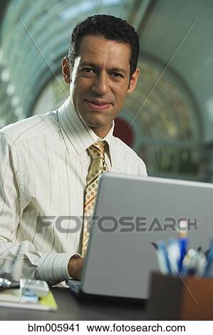 Stock Image - Hispanic businessman typing on laptop. Fotosearch