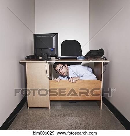 Hispanic businessman underneath desk in small office View Large Photo Image Stock Photo - Hispanic businessman underneath desk in small office. Fotosearch