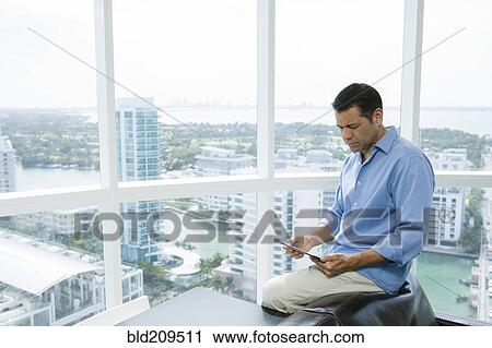 Hispanic businessman using digital tablet in office View Large Photo Image Stock Image - Hispanic businessman using digital tablet in office. Fotosearch