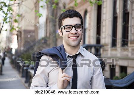 Stock Photograph - Hispanic businessman walking on city sidewalk. Fotosearch