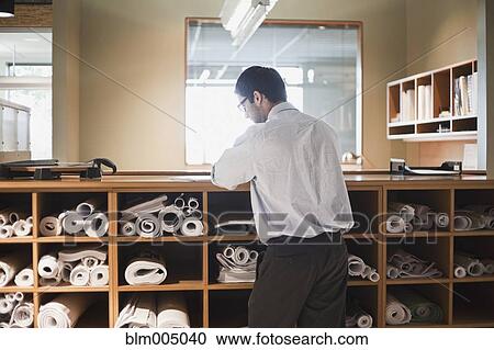 Hispanic businessman working with blueprints in office View Large Photo Image Stock Image - Hispanic businessman working with blueprints in office. Fotosearch