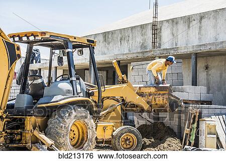Stock Photograph - Hispanic construction worker on bulldozer at construction site. Fotosearch